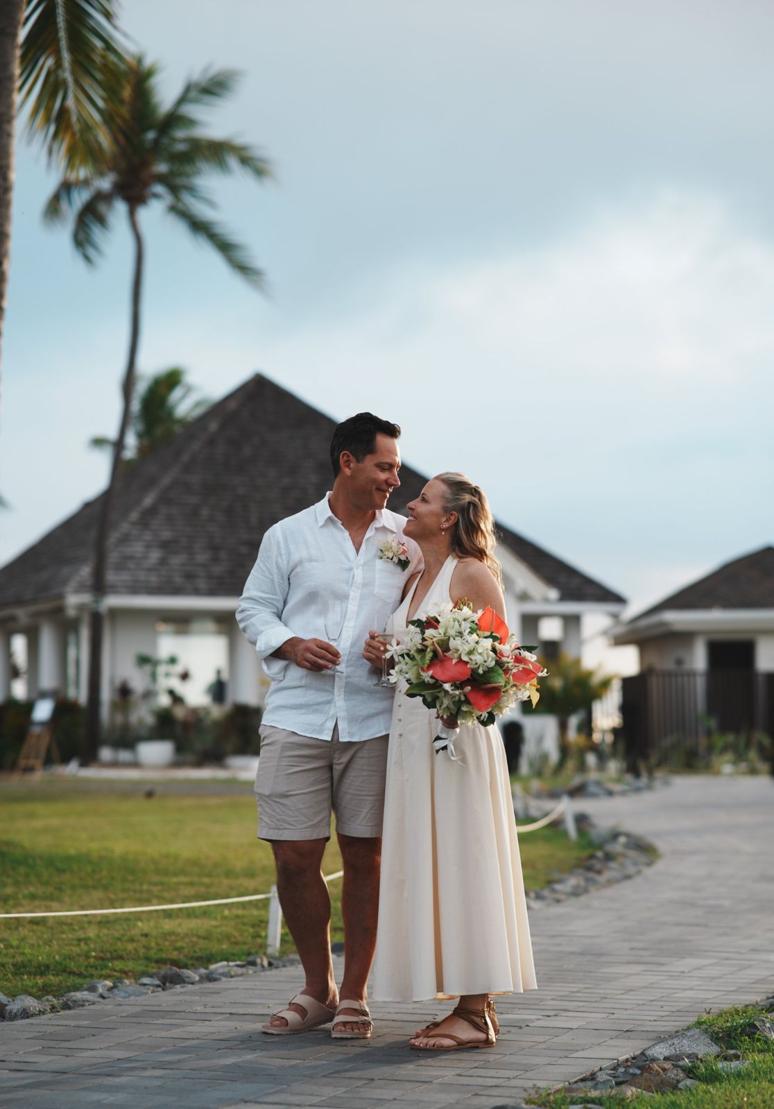 Couple with bouquet and champagne walking through a resort