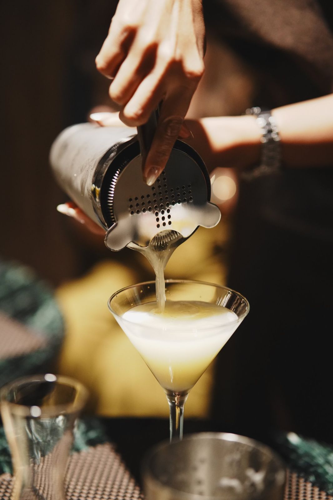 Bartender straining a cocktail into a martini glass