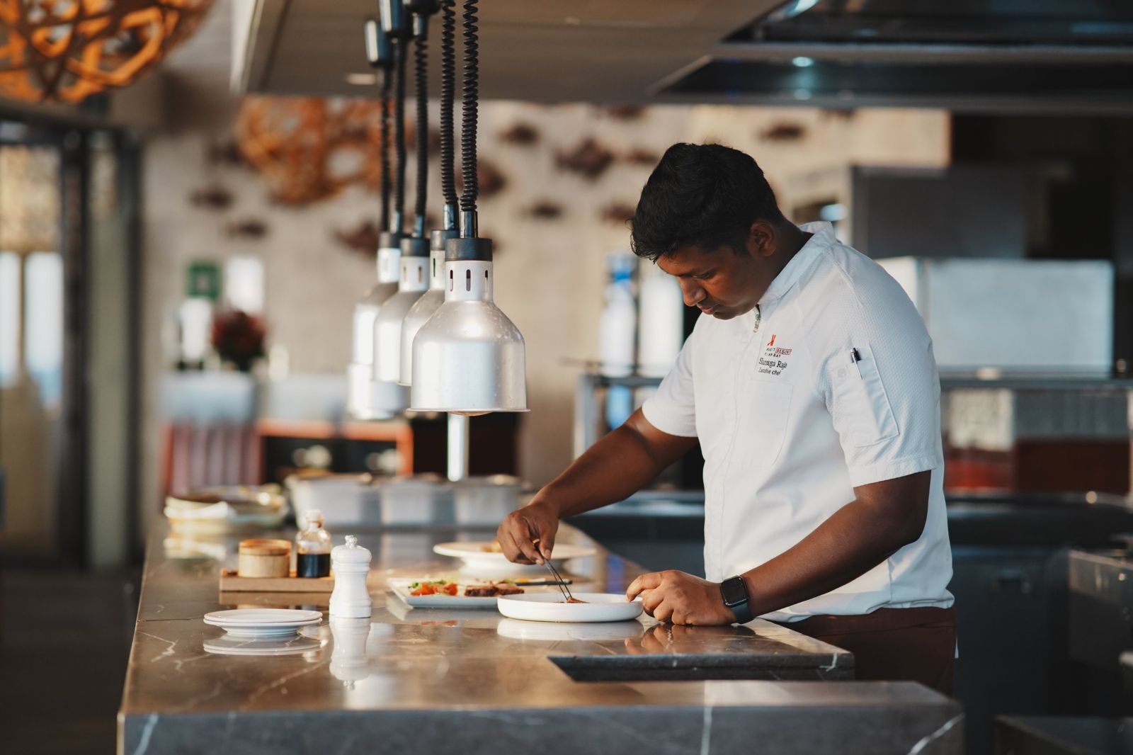 Executive chef plating a dish in a resort kitchen