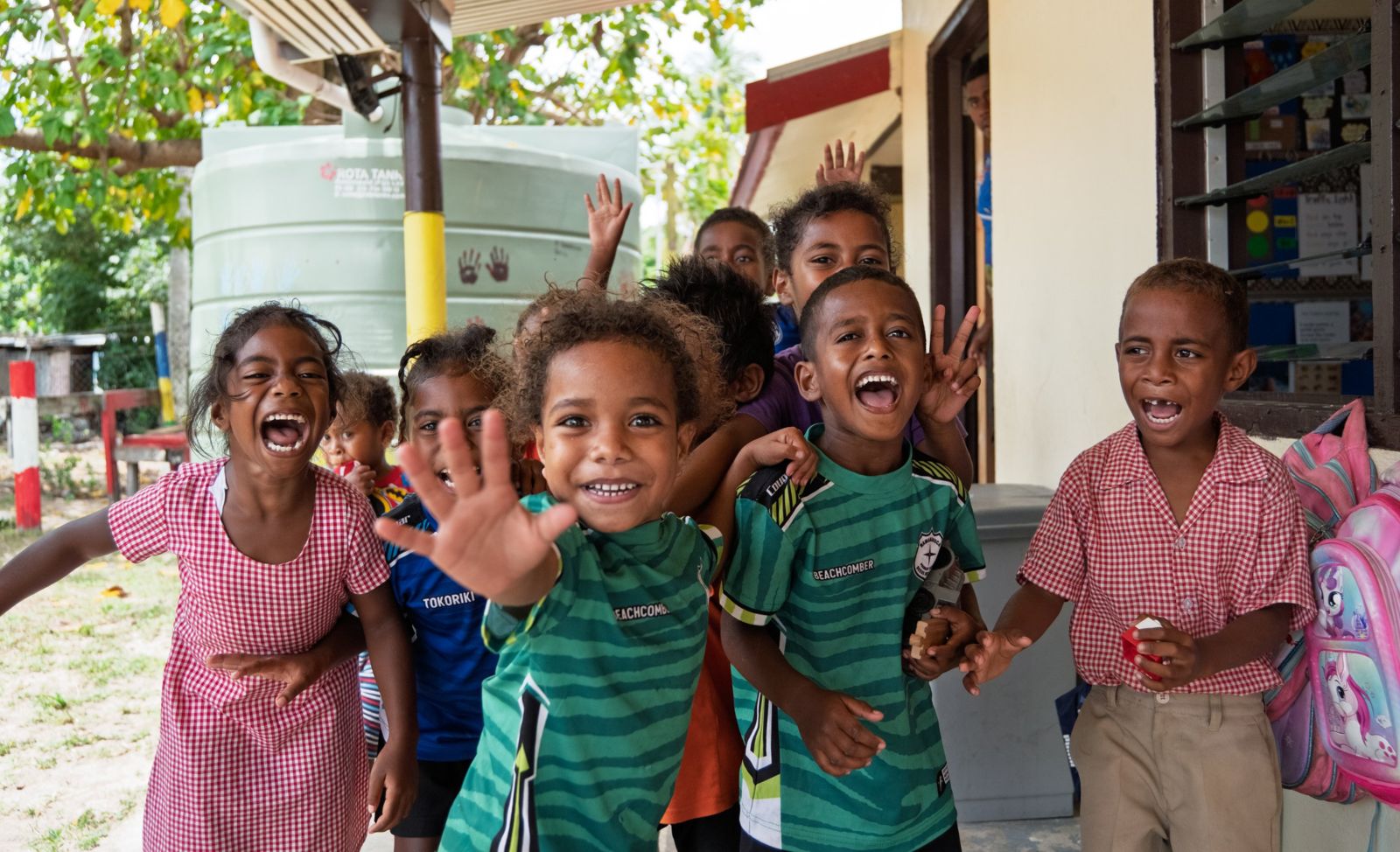 Primary school children laughing and waving outside their classroom