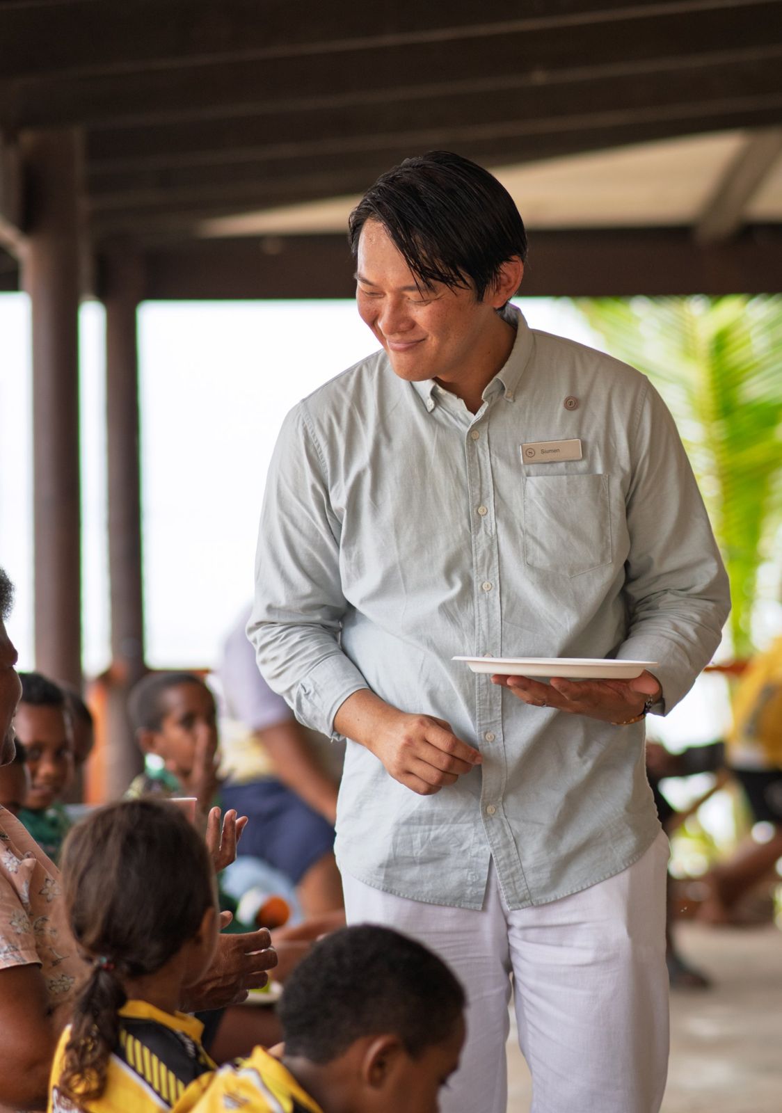 Resort manager smiling as he serves food to schoolchildren