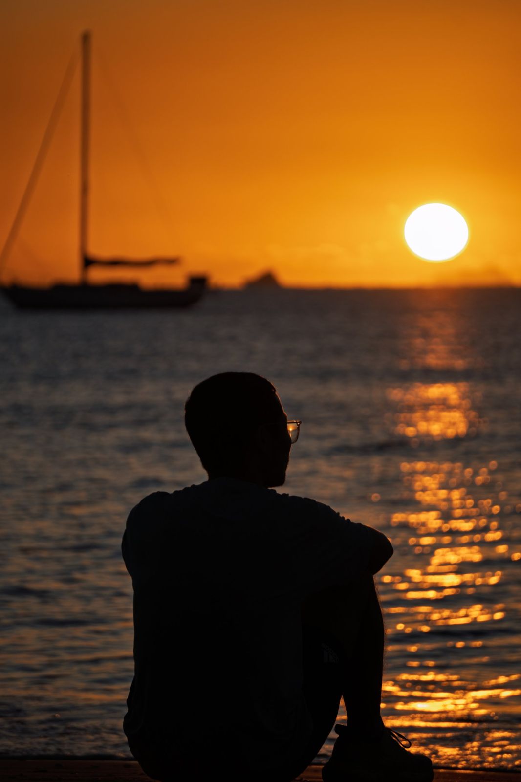 Silhouette of a man watching the sun set over the sea