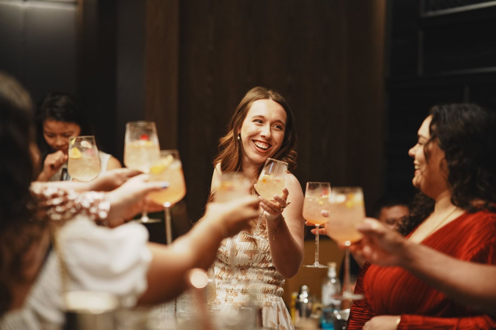 Smiling woman raising a cocktail glass with friends